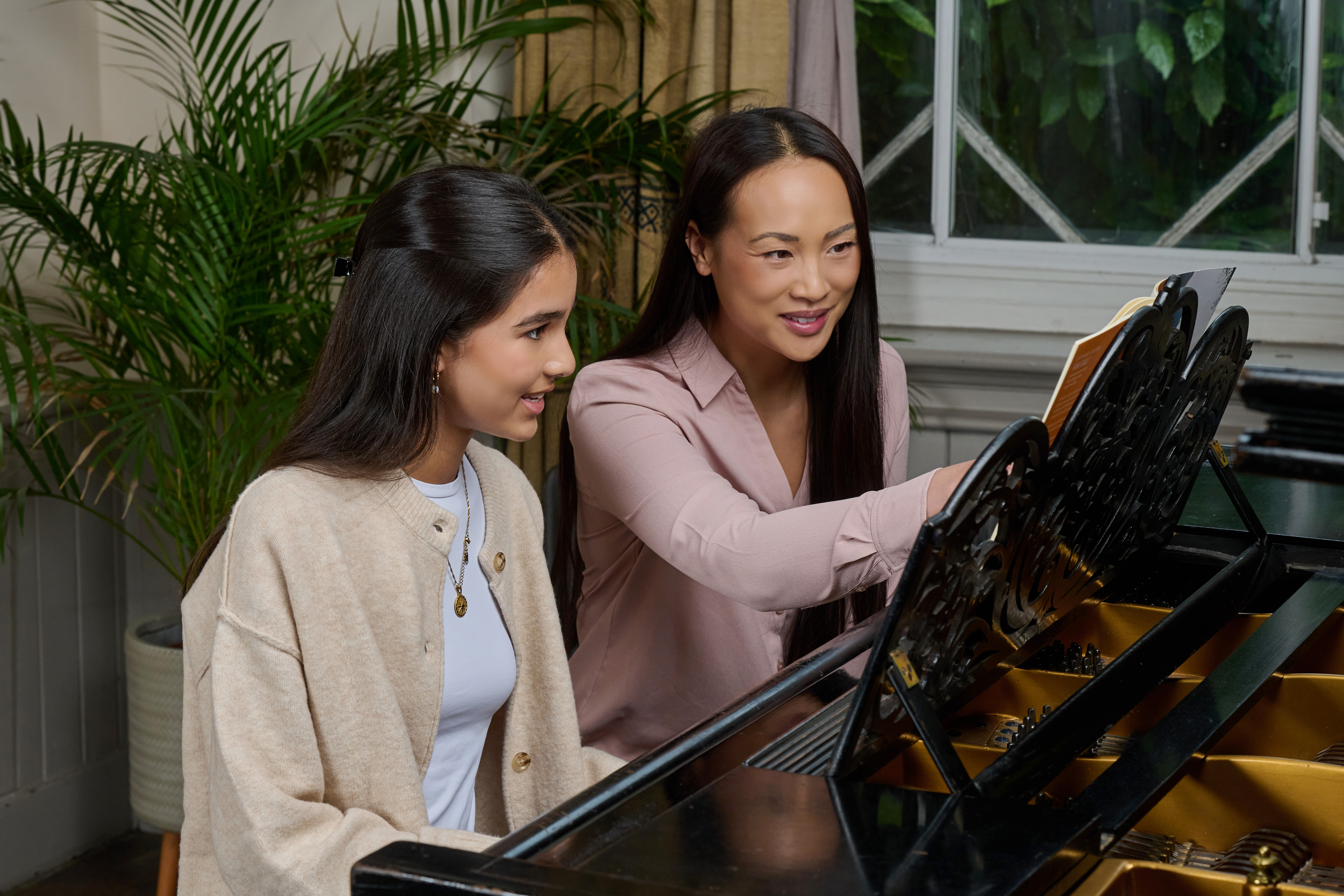 Music teacher supporting a young student at the piano